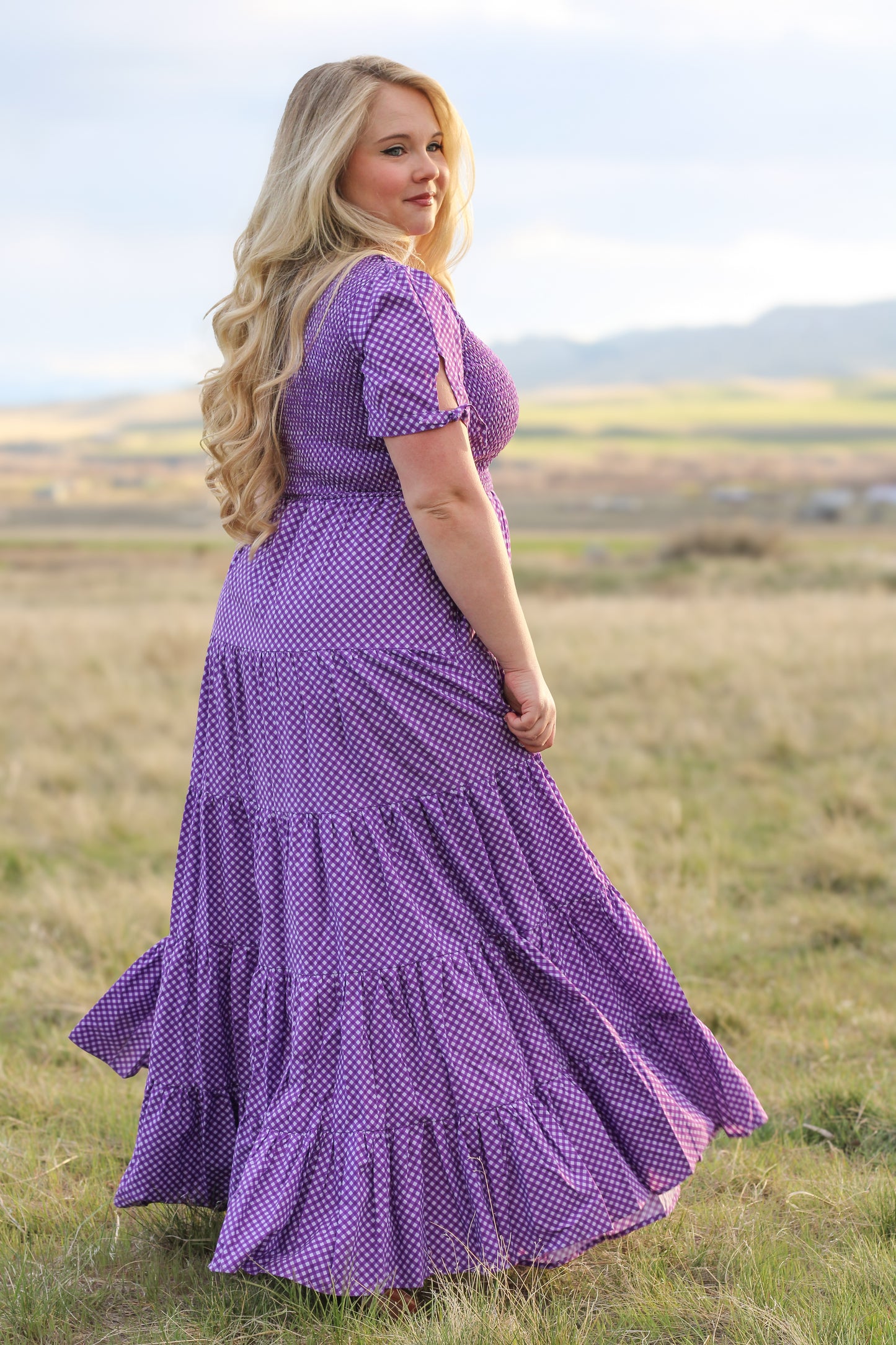 A woman wearing a purple, gingham, five-tiered maxi modest nursing dress