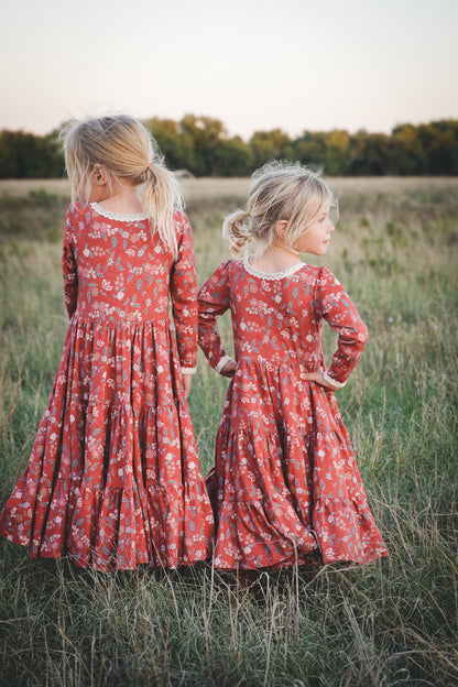 Two girls in modest red floral dresses outdoors