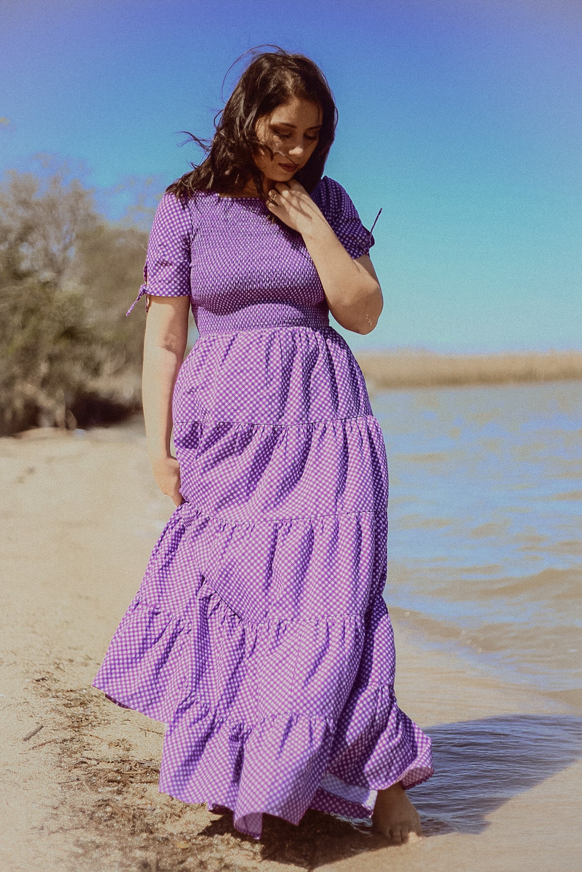 A woman wearing a purple, gingham, five-tiered maxi modest nursing dress