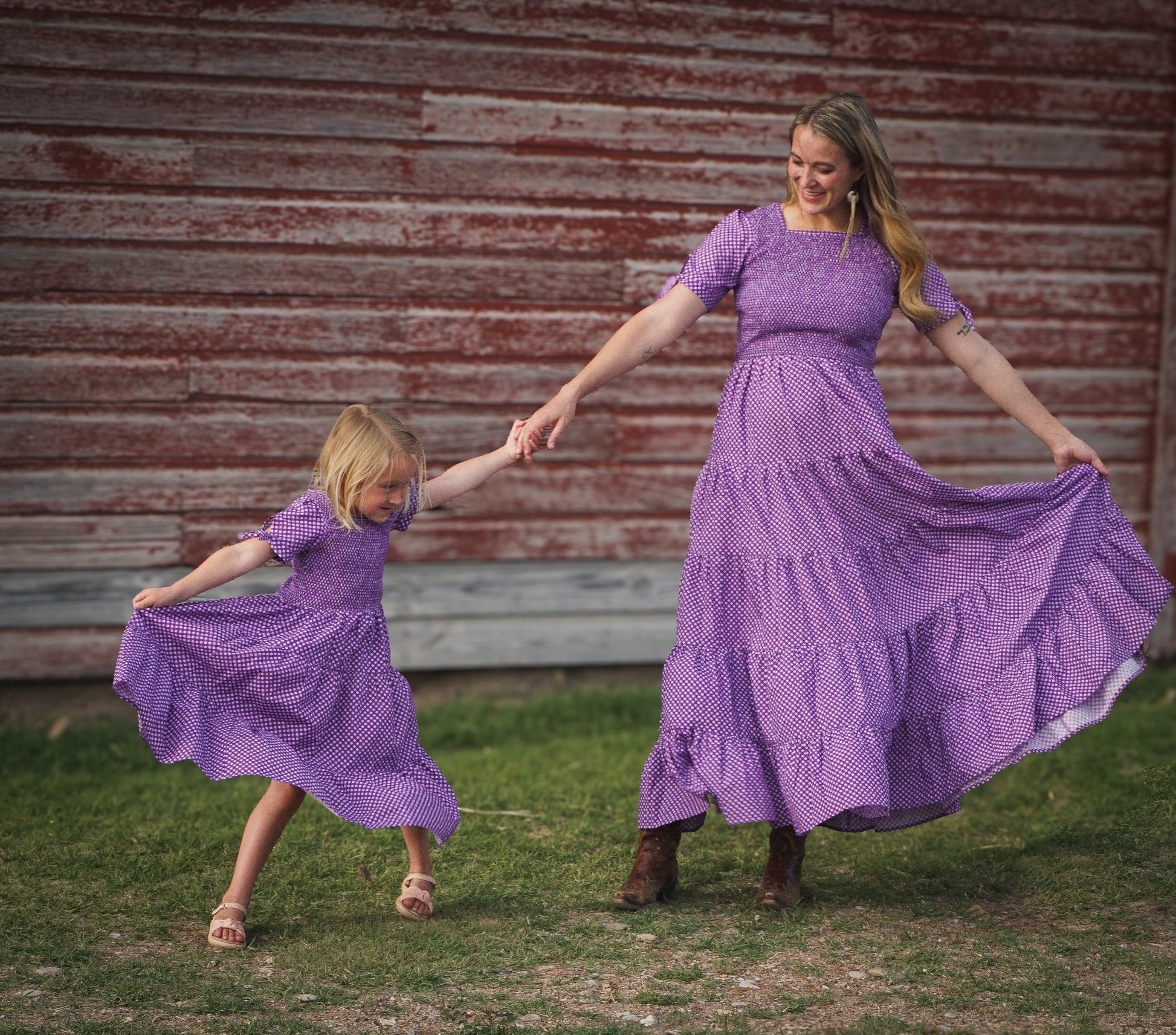 A woman wearing a purple, gingham, five-tiered maxi modest nursing dress with her daughter wearing a matching dress