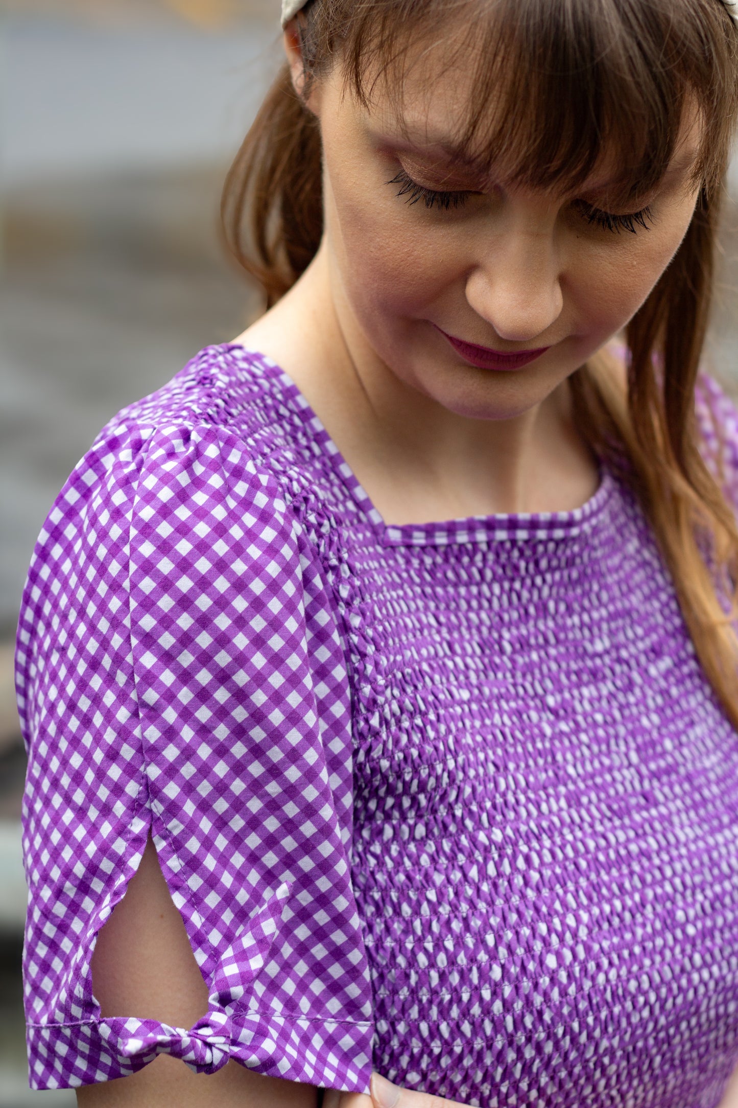 A woman wearing a purple, gingham, five-tiered maxi modest nursing dress