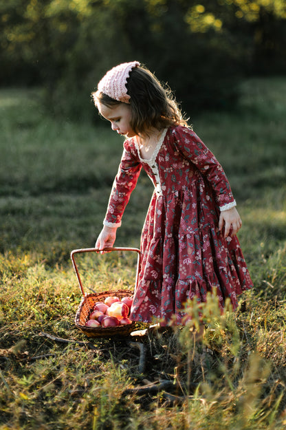 Girl in modest red floral dress with apple basket