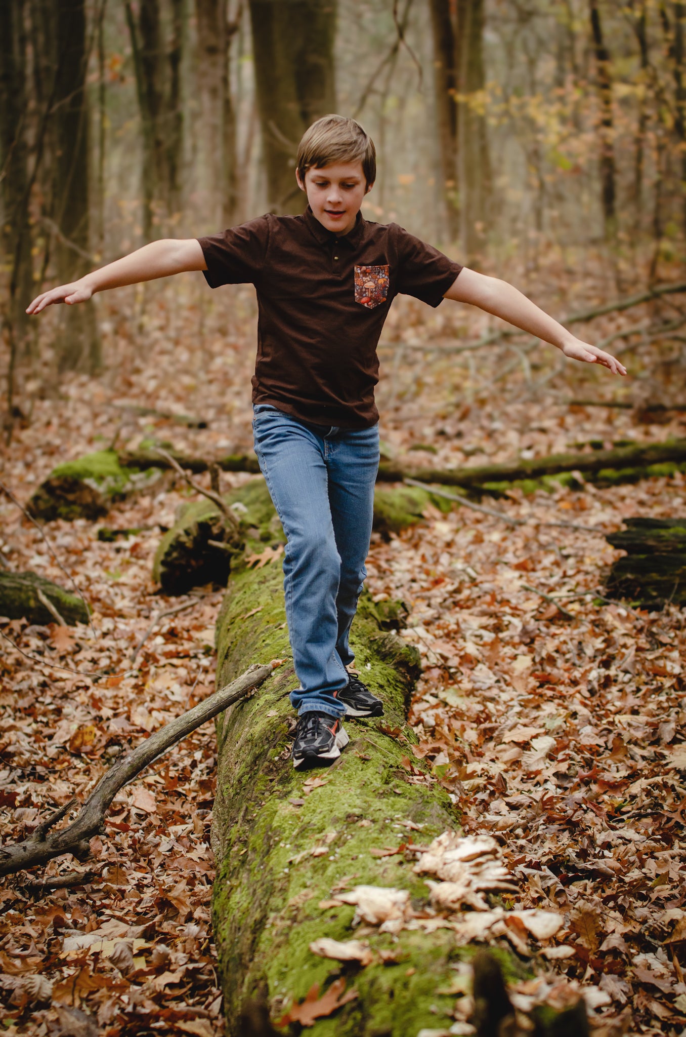 Boy balancing on log in autumn forest