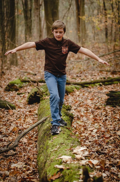 Boy balancing on log in autumn forest