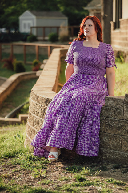 A woman wearing a purple, gingham, five-tiered maxi modest nursing dress