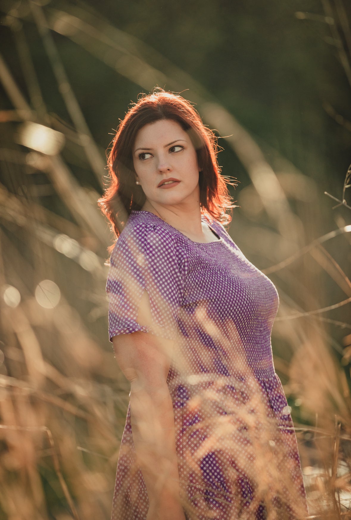 A woman wearing a purple, gingham, five-tiered maxi modest nursing dress
