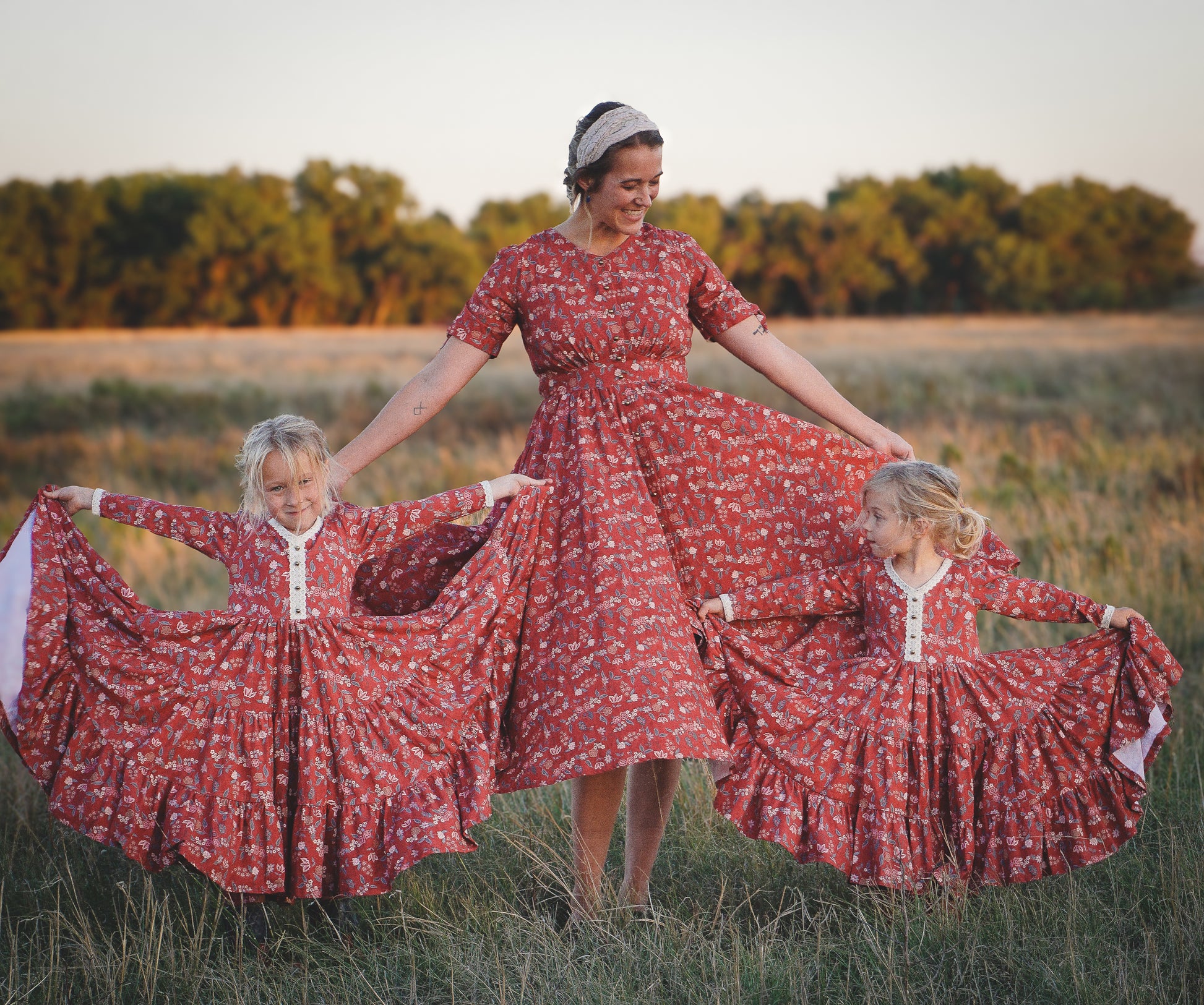 Modest nursing woman with two children in matching red floral dresses