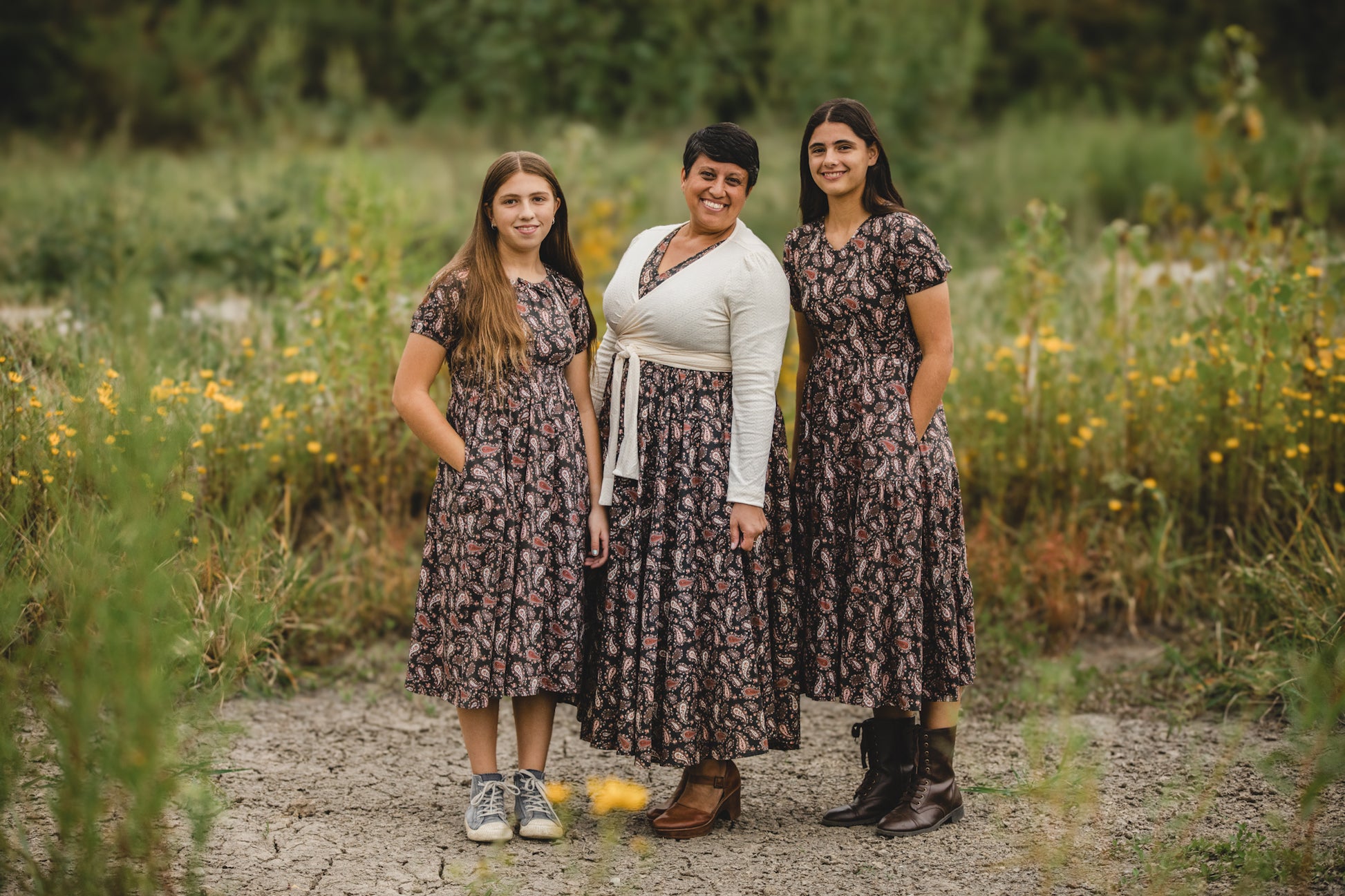 Three women in modest nursing dresses in wildflower field