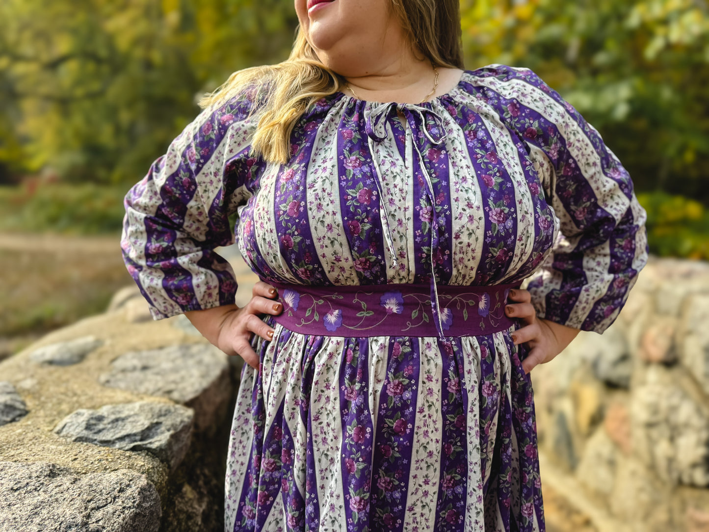 Woman wearing a modest nursing purple and white striped dress with floral patterns outdoors.