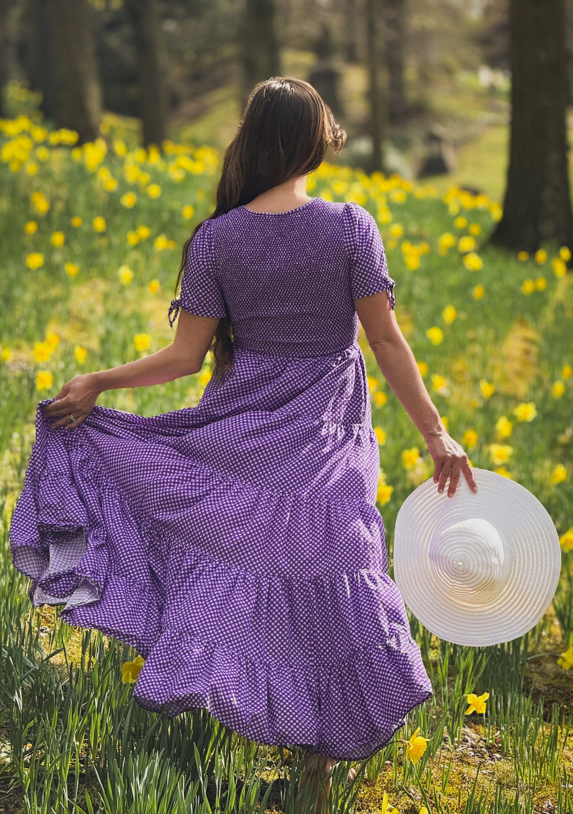 A woman wearing a purple, gingham, five-tiered maxi modest nursing dress