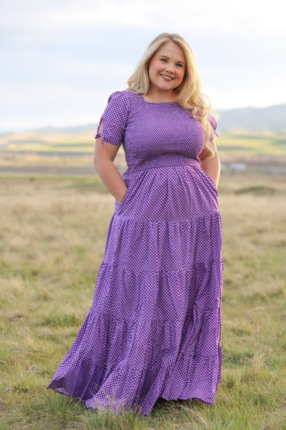 A woman wearing a purple, gingham, five-tiered maxi modest nursing dress