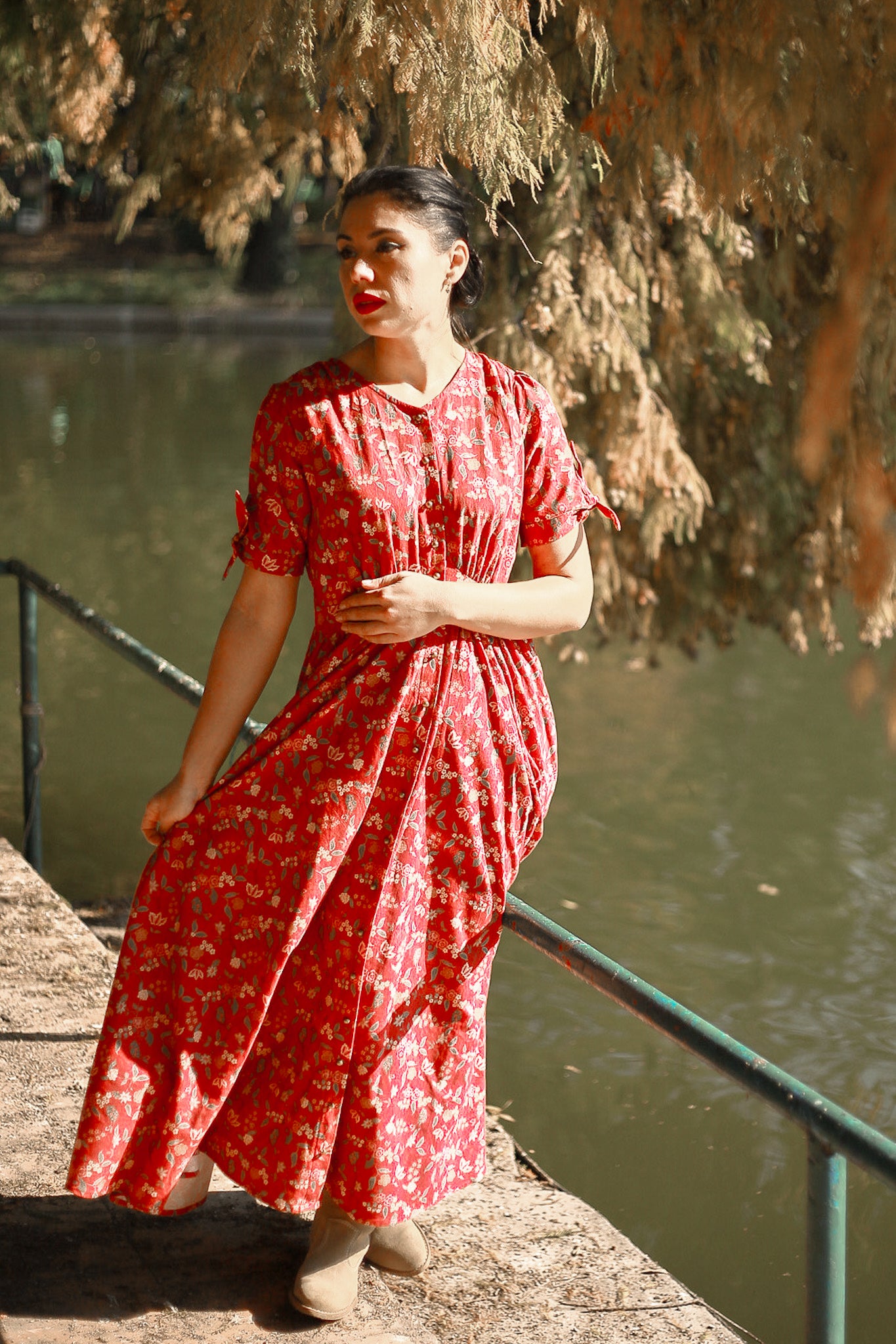 Woman in modest nursing red dress by water