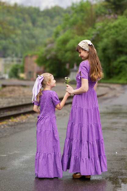 A woman wearing a purple, gingham, five-tiered maxi modest nursing dress with her daughter wearing a matching dress