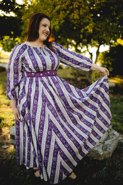 Modest nursing woman wearing purple and white patterned dress outdoors