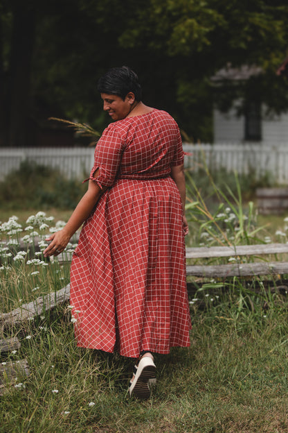 Woman in modest nursing red checkered dress garden