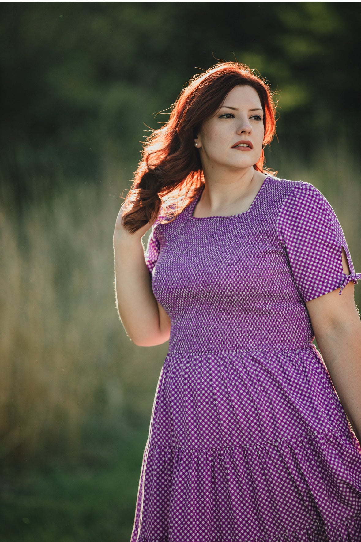 A woman wearing a purple, gingham, five-tiered maxi modest nursing dress