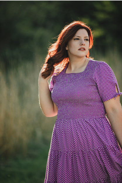 A woman wearing a purple, gingham, five-tiered maxi modest nursing dress