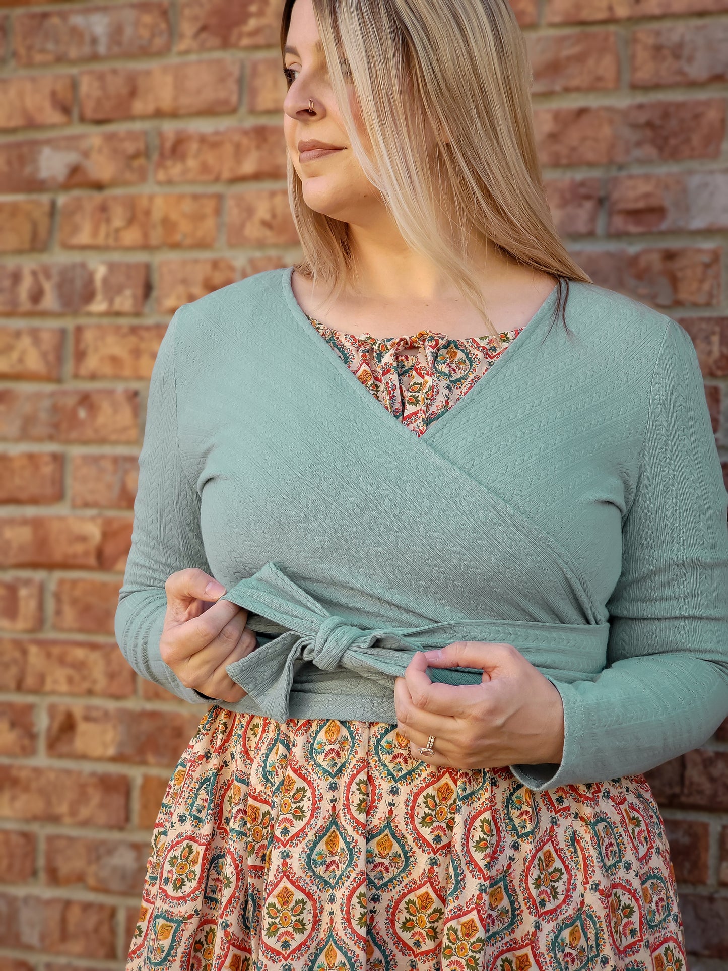 Woman in modest nursing wrap over patterned dress