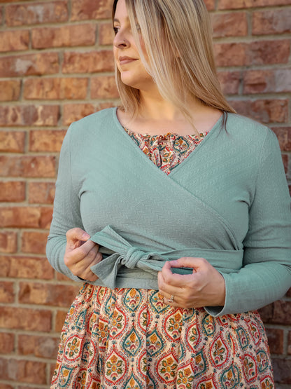 Woman in modest nursing wrap over patterned dress