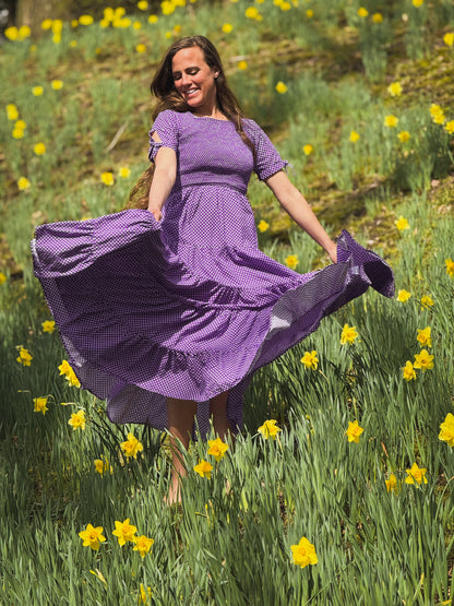 A woman wearing a purple, gingham, five-tiered maxi modest nursing dress