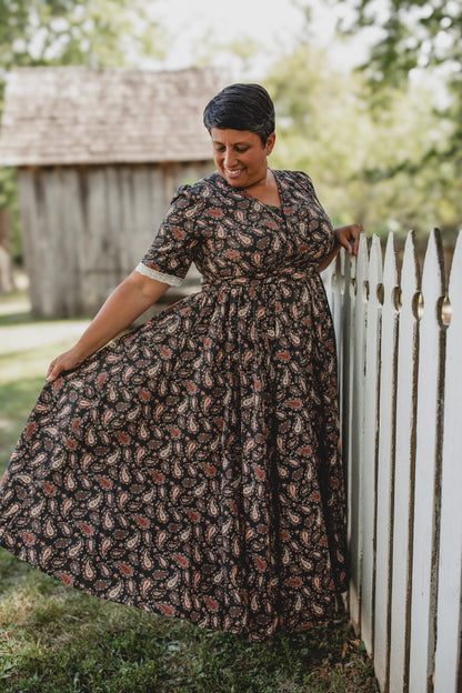 Woman in modest nursing dress by white picket fence