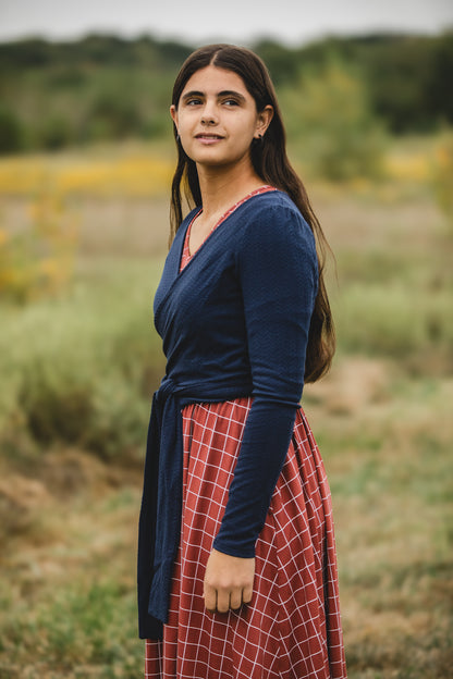 Woman in modest nursing-friendly blue top and red plaid skirt