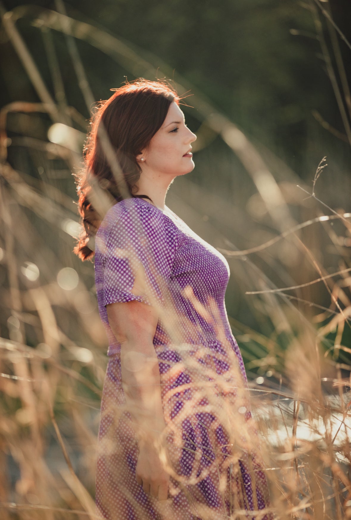 A woman wearing a purple, gingham, five-tiered maxi modest nursing dress