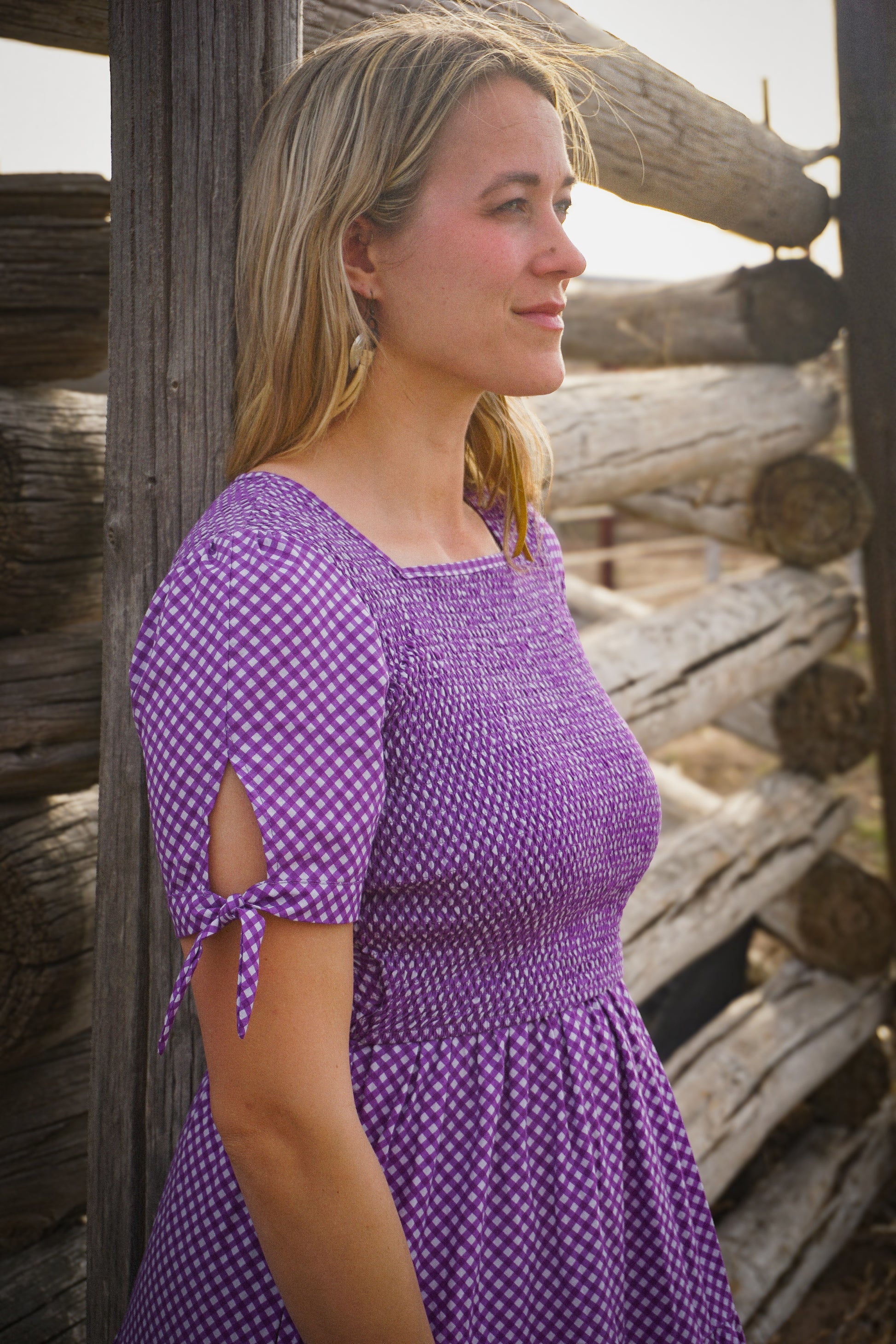 A woman wearing a purple, gingham, five-tiered maxi modest nursing dress