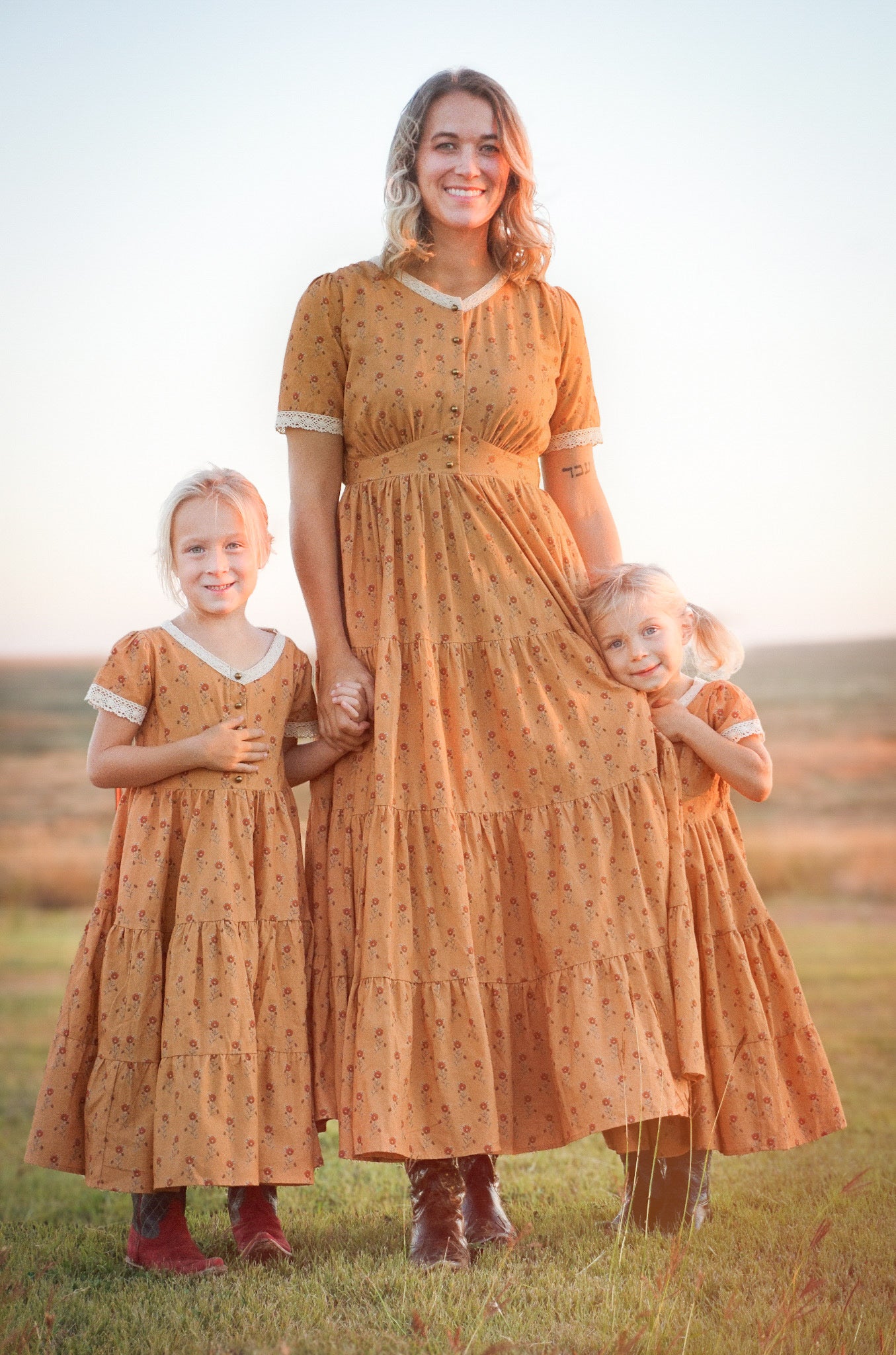 Woman in modest nursing dress with two children in field