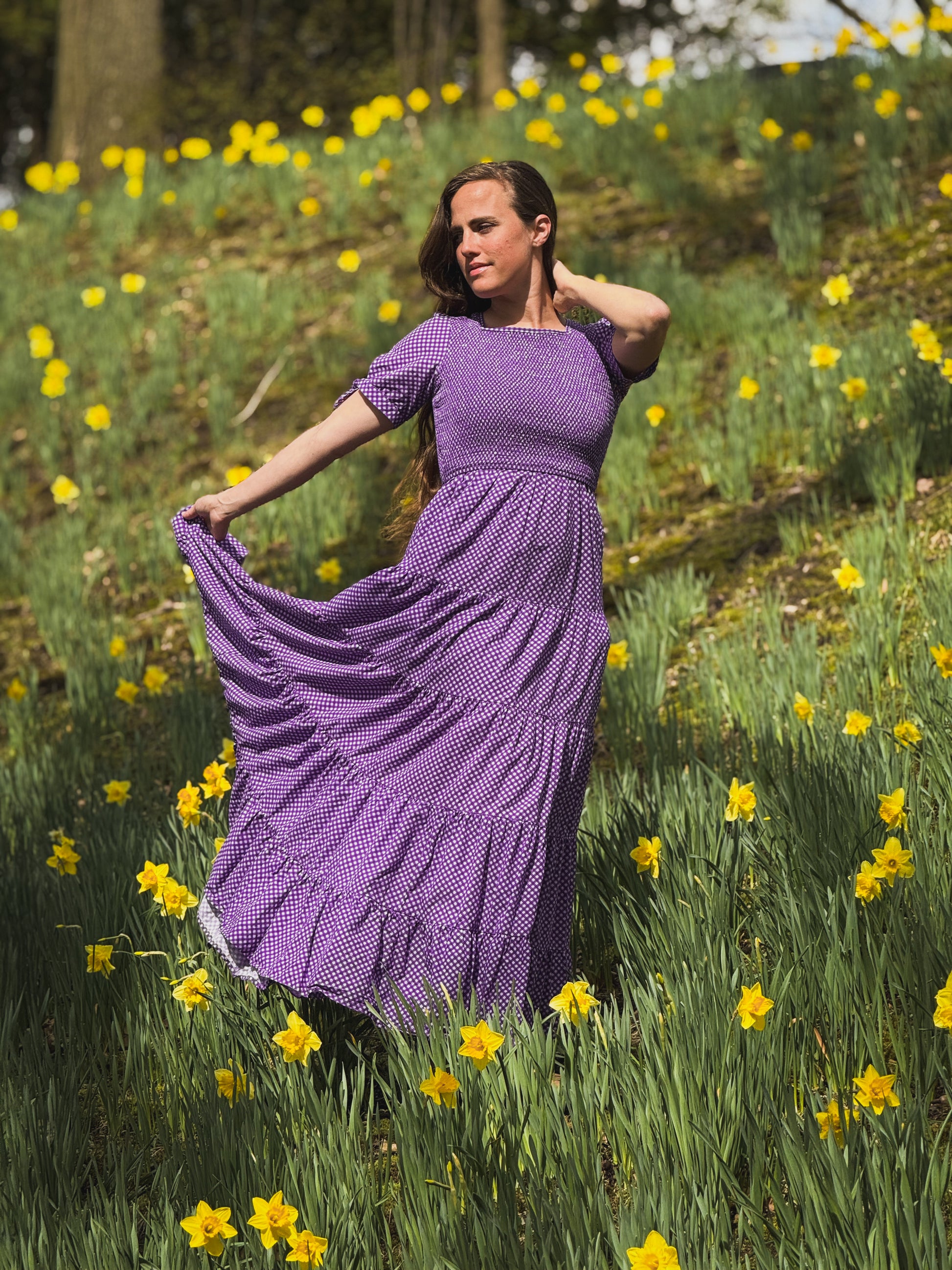 A woman wearing a purple, gingham, five-tiered maxi modest nursing dress