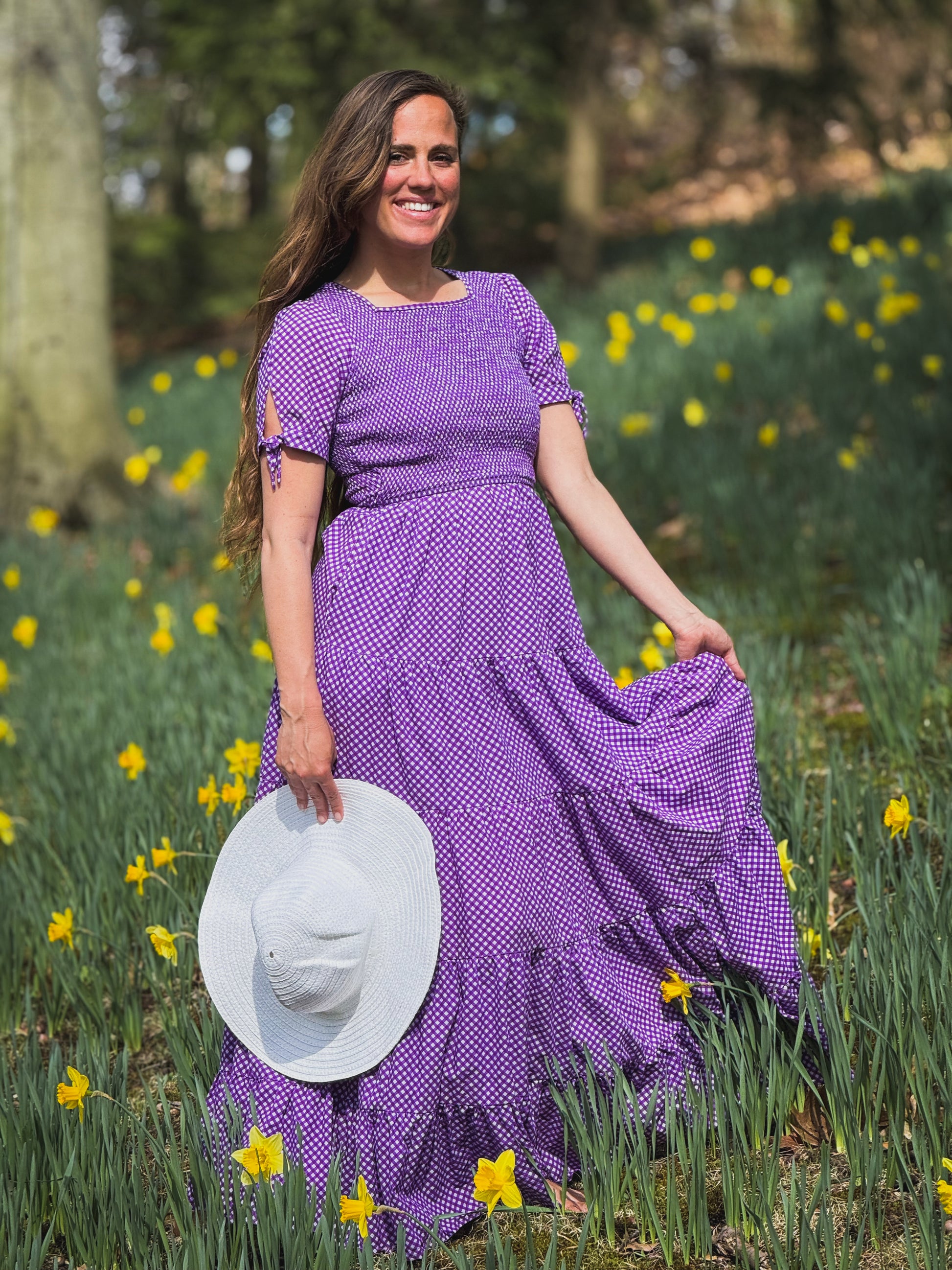 A woman wearing a purple, gingham, five-tiered maxi modest nursing dress