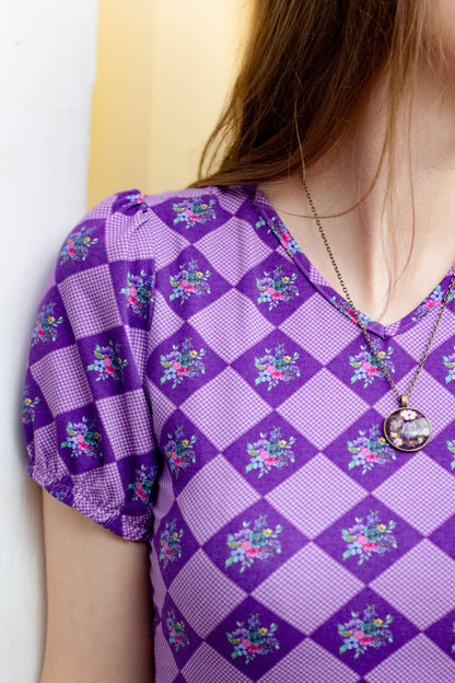 Woman in a purple checkered modest nursing dress.