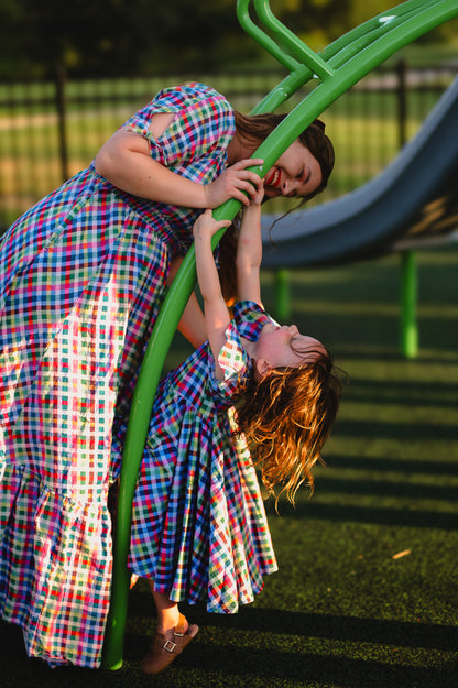 Mother and daughter in colorful modest dresses playing on a playground slide.
