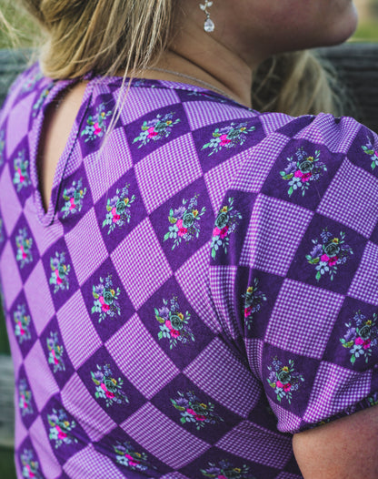 Woman in a purple checkered modest nursing dress.