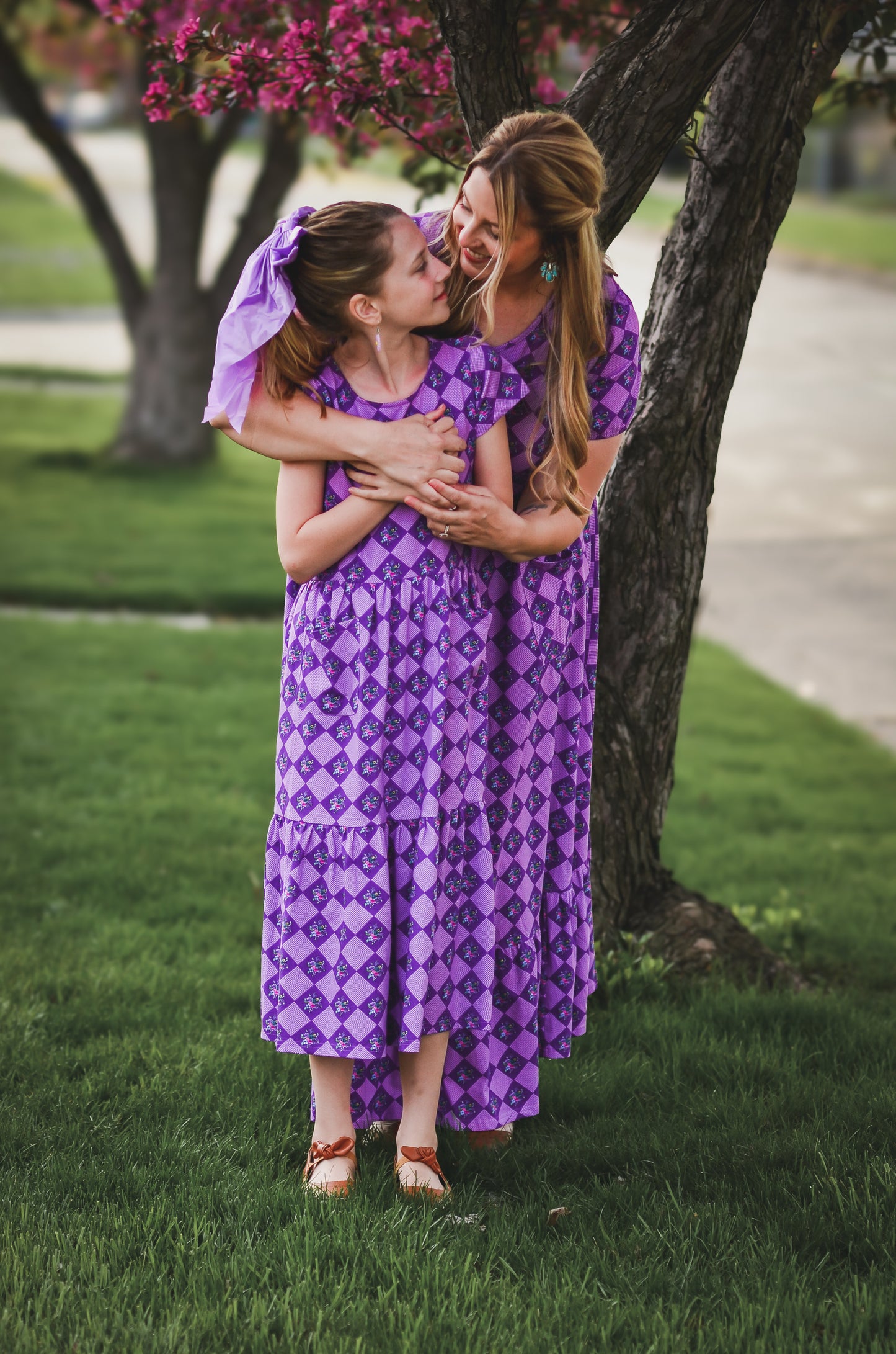 Woman in a purple checkered modest nursing dress with her daughter in a matching dress.