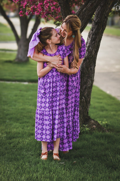 Woman in a purple checkered modest nursing dress with her daughter in a matching dress.