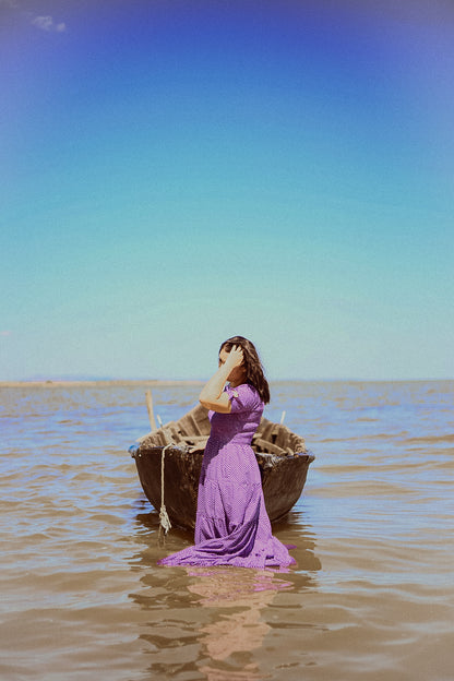 A woman wearing a purple, gingham, five-tiered maxi modest nursing dress