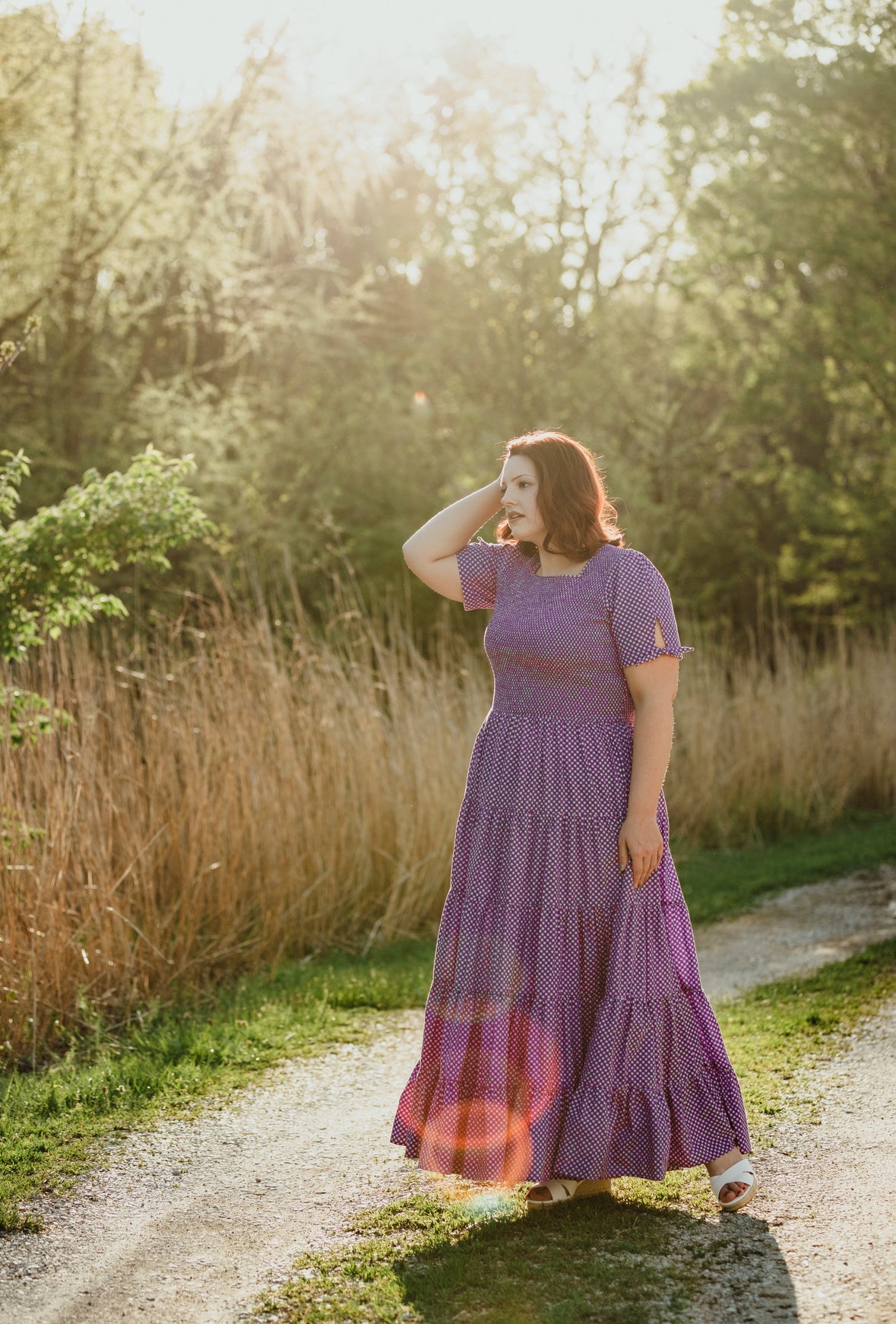 A woman wearing a purple, gingham, five-tiered maxi modest nursing dress