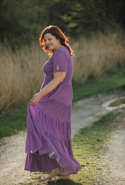 A woman wearing a purple, gingham, five-tiered maxi modest nursing dress