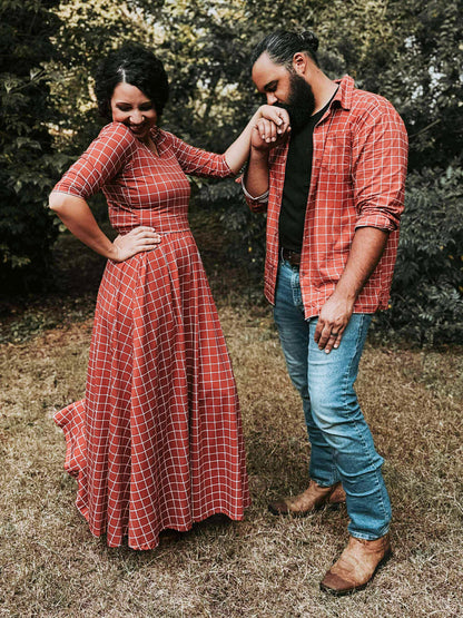 Couple in matching red plaid outfits standing outdoors.