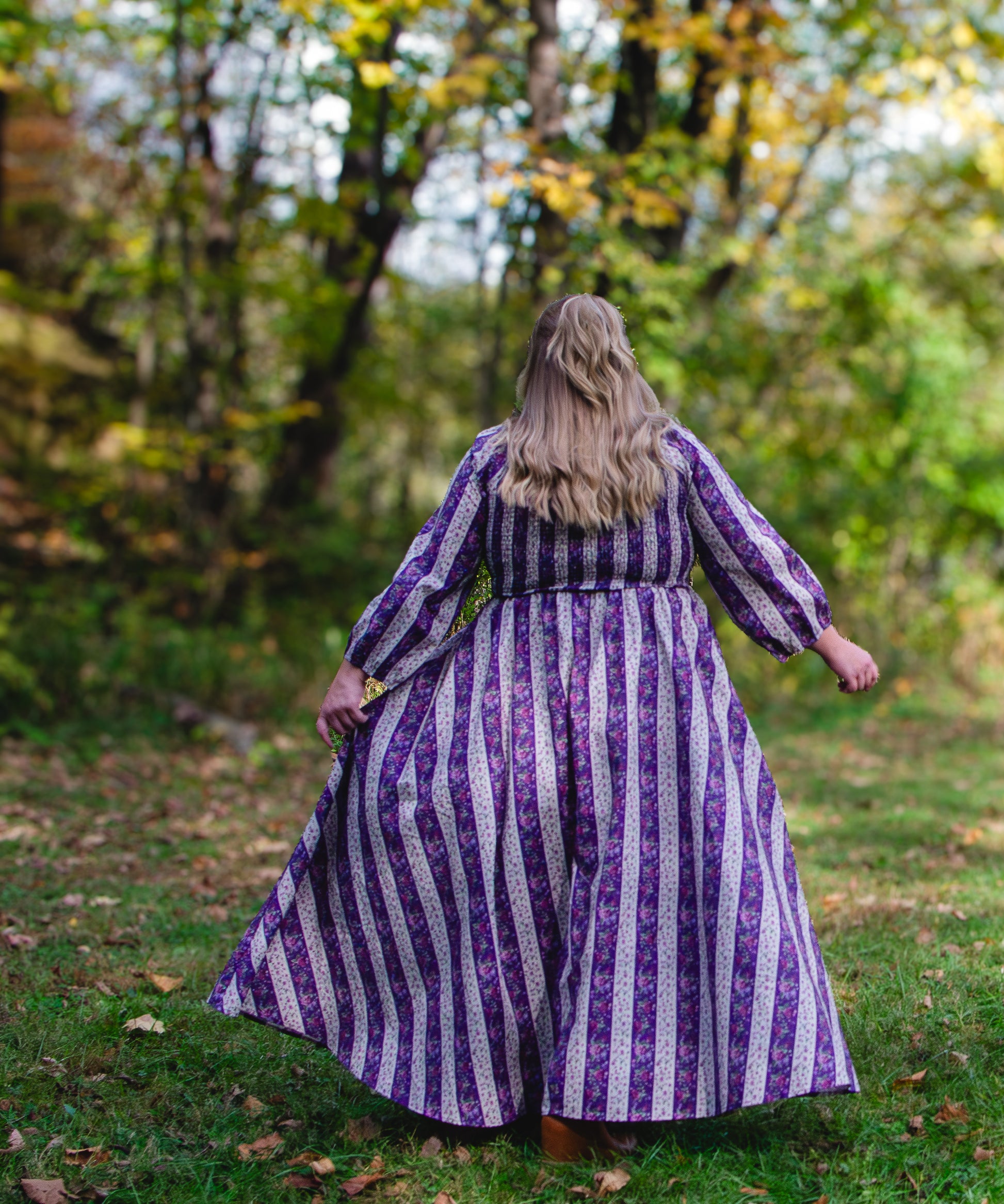 Person wearing a modest nursing purple and white striped dress standing in a forest