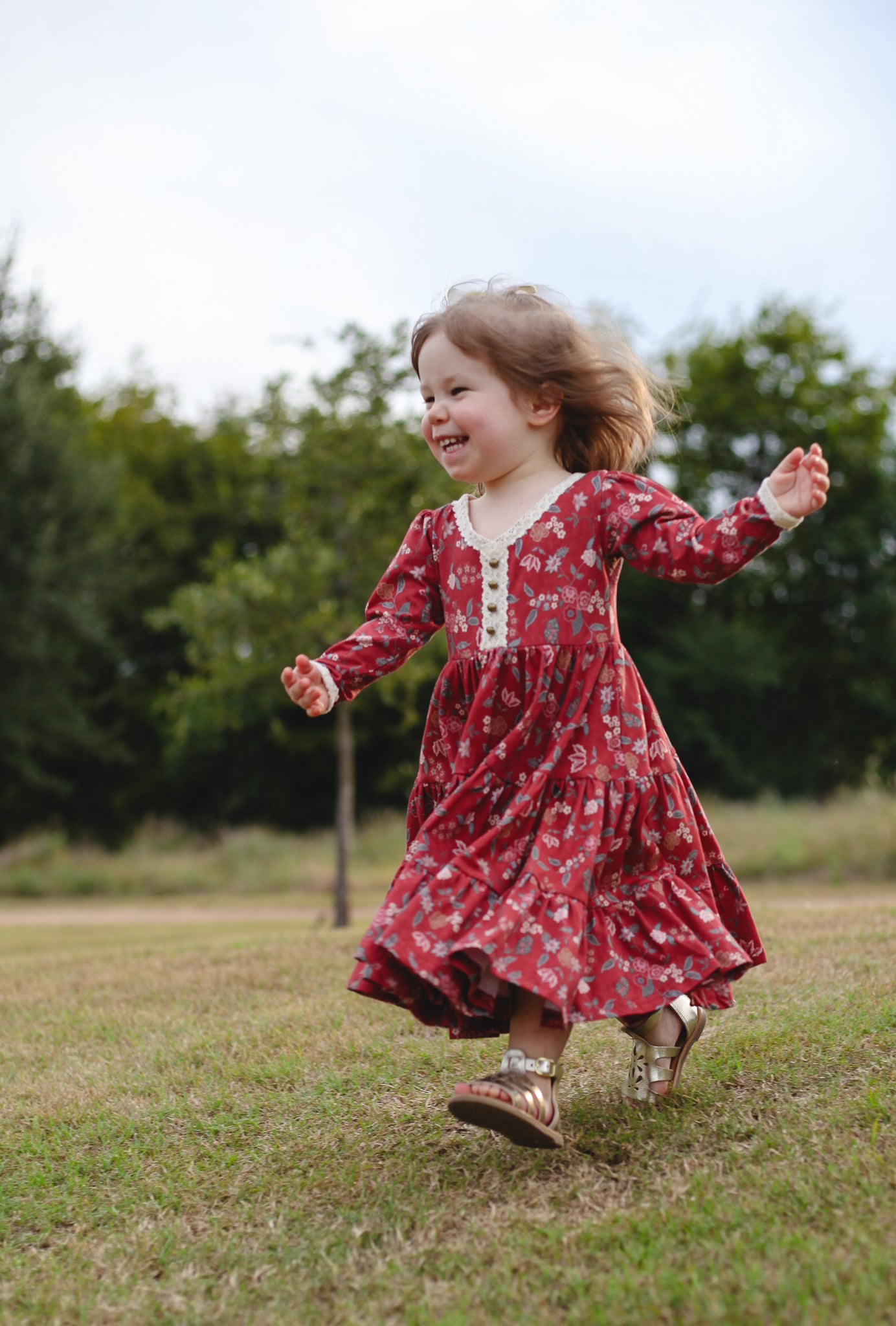 Child in modest red floral dress running outdoors